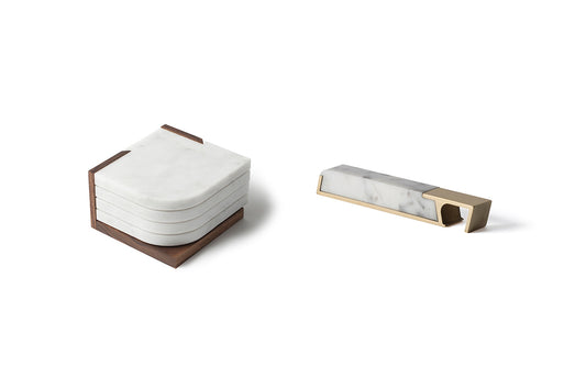 A Fire Road Bar Set featuring a set of four white marble coasters in a wooden holder, accompanied by a marble and brass Fire Road Profile Bottle Opener.