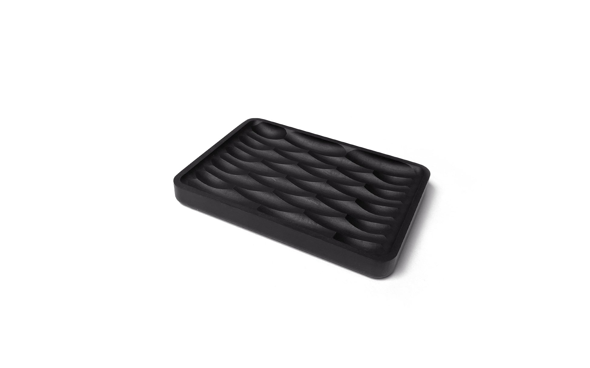 The Fire Road Deco Soap Dish is an eco-friendly black, rectangular soap dish made from recycled paper, featuring a series of wave-like grooves on its surface.